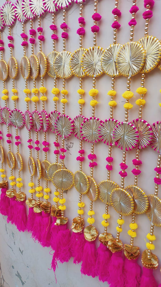 Multicolor hanging toran with pink, yellow pom-poms and golden wheel motifs